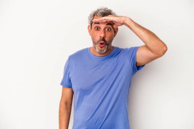 Beyaz arka planda izole edilmiş orta yaşlı beyaz bir adam uzaklara bakıyor ve elini alnına koyuyor..