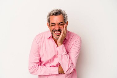 Beyaz arka planda izole edilmiş orta yaşlı beyaz bir adam mutlu bir şekilde gülüyor ve ellerini karnının üstünde tutarak eğleniyor..