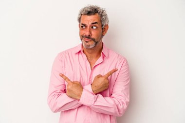 Beyaz arka plan noktalarında izole edilmiş orta yaşlı beyaz adam iki seçenek arasında seçim yapmaya çalışıyor..