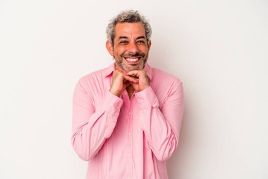 Beyaz arka planda izole edilmiş orta yaşlı beyaz bir adam ellerini çenesinin altında tutuyor, mutlu bir şekilde yana bakıyor..