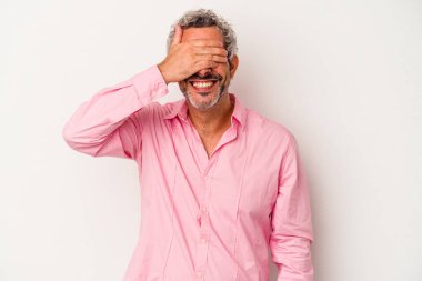 Beyaz arka planda soyutlanmış orta yaşlı beyaz bir adam elleriyle gözlerini kapatıyor, büyük bir gülümsemeyle bir sürpriz bekliyor..