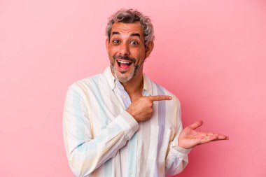 Pembe arka planda izole edilmiş orta yaşlı beyaz bir adam, elinde bir fotokopi alanı tutarken heyecanlanıyor..