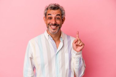 Pembe arka planda izole edilmiş orta yaşlı beyaz bir adam bir numarayı parmağıyla gösteriyor..
