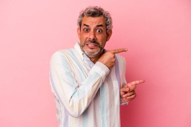 Pembe arka planda izole edilmiş orta yaşlı beyaz adam işaret parmağıyla fotokopi alanını işaret ederek şok oldu..