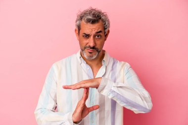 Pembe arka planda izole edilmiş orta yaşlı beyaz bir adam bir mola hareketi gösteriyor..