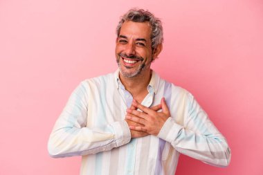 Pembe arka planda izole edilmiş orta yaşlı beyaz bir adam, dostane bir ifadeye sahip, avuçlarını göğsüne bastırıyor. Aşk konsepti.