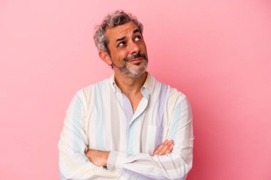 Pembe arka planda izole edilmiş orta yaşlı beyaz adam hedeflerine ve amaçlarına ulaşma hayali kuruyor.