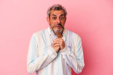 Orta yaşlı beyaz bir adam pembe arka planda izole edilmiş korkmuş ve korkmuş..