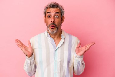 Orta yaşlı beyaz bir adam pembe arka planda izole edilmiş, şaşırmış ve şok olmuş..