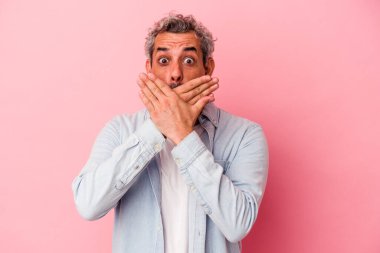 Pembe arka planda izole edilmiş orta yaşlı beyaz bir adam elleriyle ağzını kapatırken şok oldu..