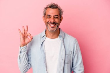 Orta yaşlı beyaz bir adam pembe arka planda izole edilmiş neşeli ve kendinden emin..