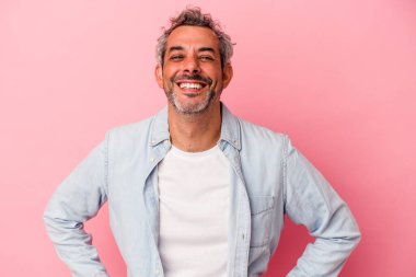 Orta yaşlı, beyaz bir adam pembe arka planda izole edilmiş. Kendine güvenen, ellerini kalçasından ayırmayan..