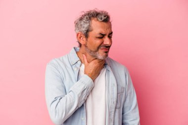 Pembe arka planda izole edilmiş orta yaşlı beyaz bir adam virüs veya enfeksiyon yüzünden boğazında ağrı hissediyor..