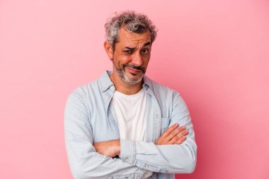 Orta yaşlı beyaz bir adam pembe arka planda izole edilmiş şüpheli, belirsiz, seni muayene ediyor..