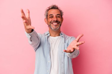 Pembe arka planda izole edilmiş orta yaşlı beyaz bir adam kameraya sarıldığı için kendinden emin hissediyor..