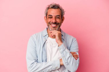 Orta yaşlı beyaz adam pembe arka planda izole edilmiş mutlu ve kendinden emin gülümsüyor, çenesine elleriyle dokunuyor..
