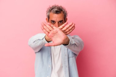 Pembe arka planda izole edilmiş orta yaşlı beyaz bir adam inkar jesti yapıyor.