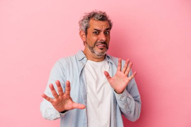 Pembe arka planda izole edilmiş orta yaşlı beyaz bir adam yakın bir tehlike nedeniyle şoka uğruyor.