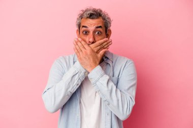 Orta yaşlı beyaz bir adam pembe arka planda izole edilmiş ağzı kapalı ve elleri endişeli görünüyor..