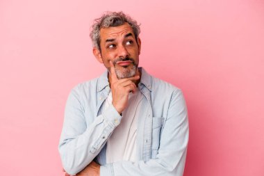 Orta yaşlı, beyaz bir adam pembe arka planda izole edilmiş, bir strateji planlıyor, bir işin nasıl olacağını düşünüyor..