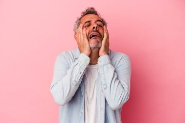 Orta yaşlı beyaz bir adam pembe arka planda izole edilmiş ağlayan, bir şeyden mutsuz, acı ve kafa karışıklığı konsepti..