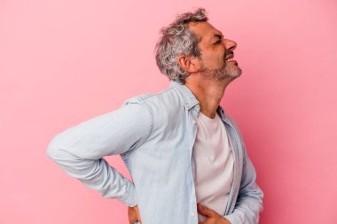 Orta yaşlı beyaz bir adam pembe arka planda izole edilmiş sırt ağrısı çekiyor..