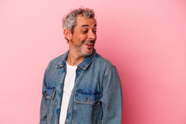 Pembe arka planda soyutlanmış orta yaşlı beyaz bir adam gülümsüyor, neşeli ve keyifli görünüyor..