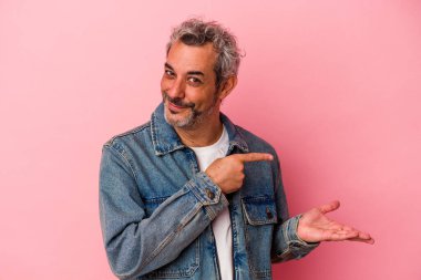 Pembe arka planda izole edilmiş orta yaşlı beyaz bir adam, elinde bir fotokopi alanı tutarken heyecanlanıyor..