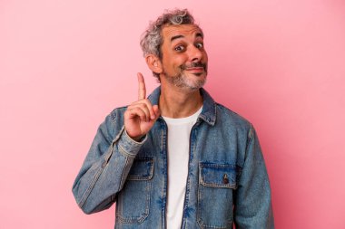 Pembe arka planda izole edilmiş orta yaşlı beyaz bir adam bir numarayı parmağıyla gösteriyor..