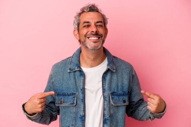 Orta yaşlı, beyaz bir adam pembe arka planda izole edilmiş. Parmakları aşağıda, olumlu hisler içinde..