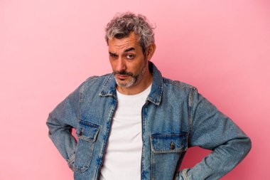 Orta yaşlı beyaz bir adam pembe arka planda izole edilmiş hoşnutsuzca kaşlarını çatmış, kollarını kavuşturmuş..