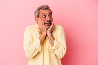 Orta yaşlı beyaz bir adam pembe arka planda izole edilmiş korkmuş ve korkmuş..