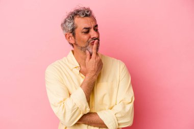 Pembe arka planda izole edilmiş orta yaşlı beyaz bir adam bir sır saklıyor ya da sessizlik istiyor..