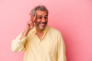 Pembe arka planda izole edilmiş orta yaşlı beyaz bir adam iki numarayı parmaklarıyla gösteriyor..