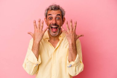 Pembe arka planda izole edilmiş orta yaşlı beyaz adam on numarayı elleriyle gösteriyor..