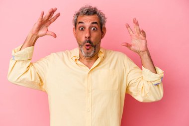 Pembe arka planda izole edilmiş orta yaşlı beyaz bir adam zaferi ya da başarıyı kutluyor, şaşırıyor ve şok oluyor..