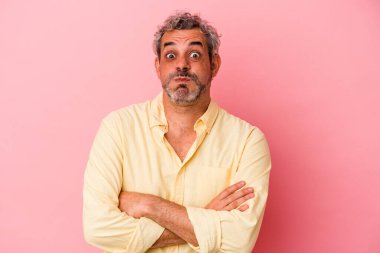 Pembe arka planda izole edilmiş orta yaşlı beyaz adam yanaklarına üflüyor, yorgun bir ifade takınıyor. Yüz ifadesi kavramı.