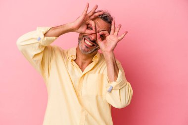 Pembe arka planda izole edilmiş orta yaşlı, beyaz bir adam gözlerinde sorun olmadığını gösteriyor.