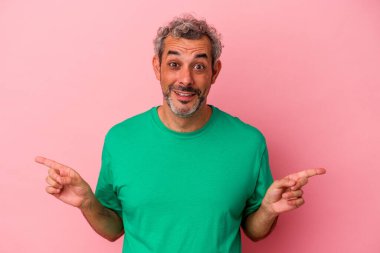 Pembe arka planda izole edilmiş orta yaşlı beyaz bir adam farklı fotokopi alanlarını gösteriyor, birini seçiyor, parmaklarıyla gösteriyor..