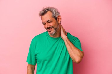 Pembe arka planda izole edilmiş orta yaşlı beyaz bir adam stresten dolayı boynu ağrıyor, masaj yapıyor ve elle dokunuyor..