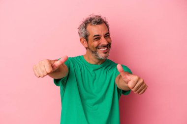 Orta yaşlı beyaz bir adam pembe arka planda izole edilmiş. Baş parmağını kaldırıyor, gülümsüyor ve kendinden emin..