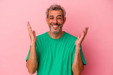 Pembe arka planda izole edilmiş orta yaşlı beyaz bir adam yüksek sesle gülüyor ve elini göğsüne koyuyor..