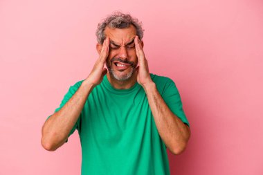Orta yaşlı beyaz bir adam pembe arka planda izole edilmiş tapınaklara dokunuyor ve baş ağrısı çekiyor..