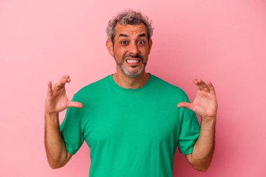 Orta yaşlı beyaz bir adam pembe arka planda izole edilmiş. Elinde avuç içi olan bir şeyle kameraya sunuyor..