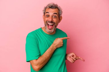 Pembe arka planda izole edilmiş orta yaşlı beyaz bir adam işaret parmağıyla işaret ederek heyecanlanıyor..