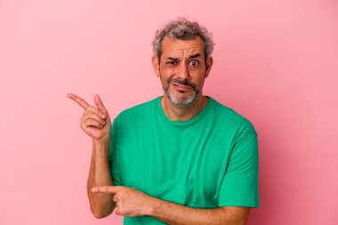 Pembe arka planda izole edilmiş orta yaşlı beyaz adam işaret parmağıyla fotokopi alanını işaret ederek şok oldu..