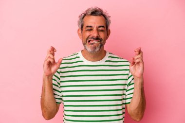 Orta yaşlı beyaz bir adam pembe arka planda izole edilmiş şans dilemek için şans diliyor.