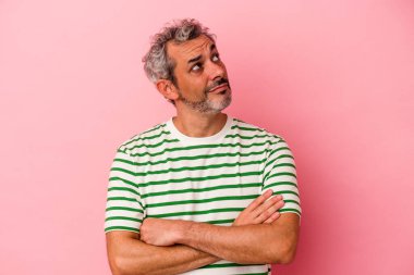 Pembe arka planda izole edilmiş orta yaşlı beyaz adam hedeflerine ve amaçlarına ulaşma hayali kuruyor.