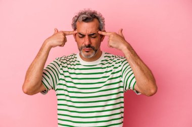 Pembe arka planda izole edilmiş orta yaşlı beyaz bir adam bir göreve odaklanmış, işaret parmaklarını işaret ediyor..