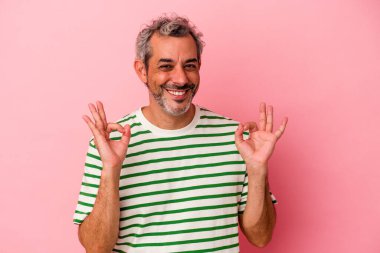 Orta yaşlı beyaz bir adam pembe arka planda izole edilmiş neşeli ve kendinden emin..